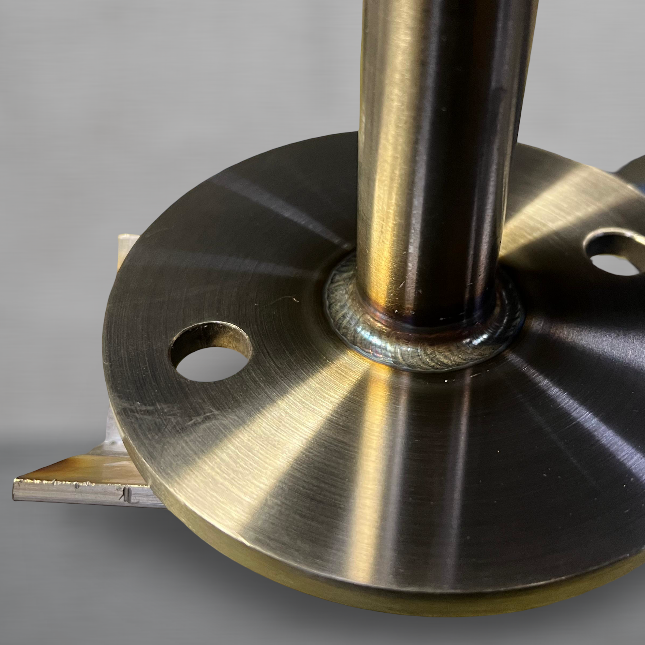 Nahaufnahme eines metallenen Flansches mit einem vertikalen Rohr und Schweißnaht.