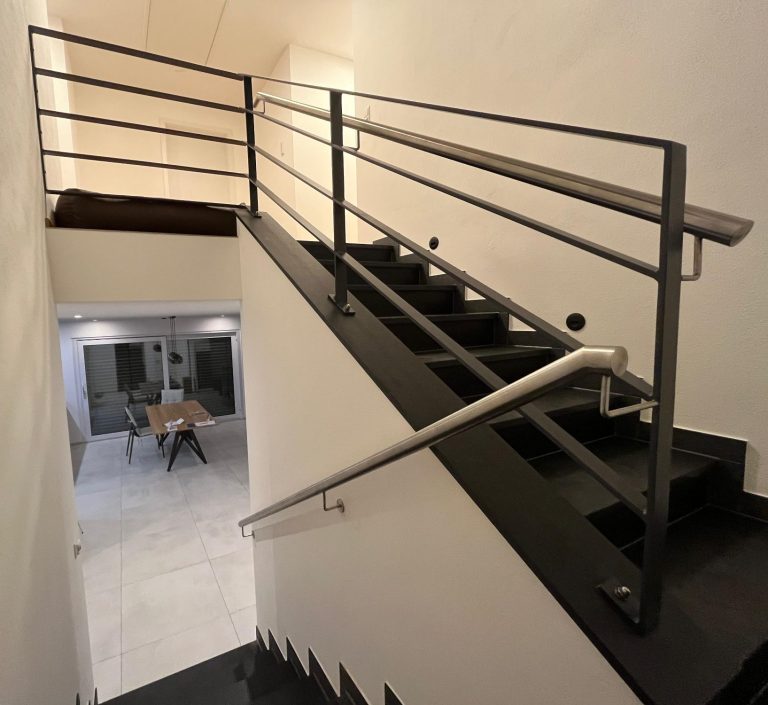 Treppenhaus mit moderner Geländerkonstruktion und Blick auf den unteren Raum.